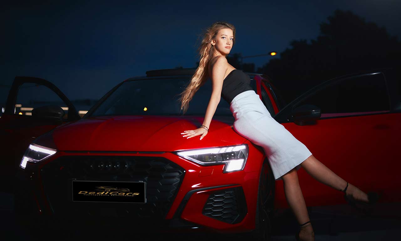 Kobieta opierająca się o maskę czerwonego samochodu Audi S3 Quattro wypożyczalnia Dedicars