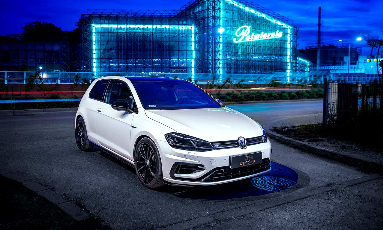 Sportowy Volkswagen Golf 7,5R w kolorze białym na tle neonowego budynku