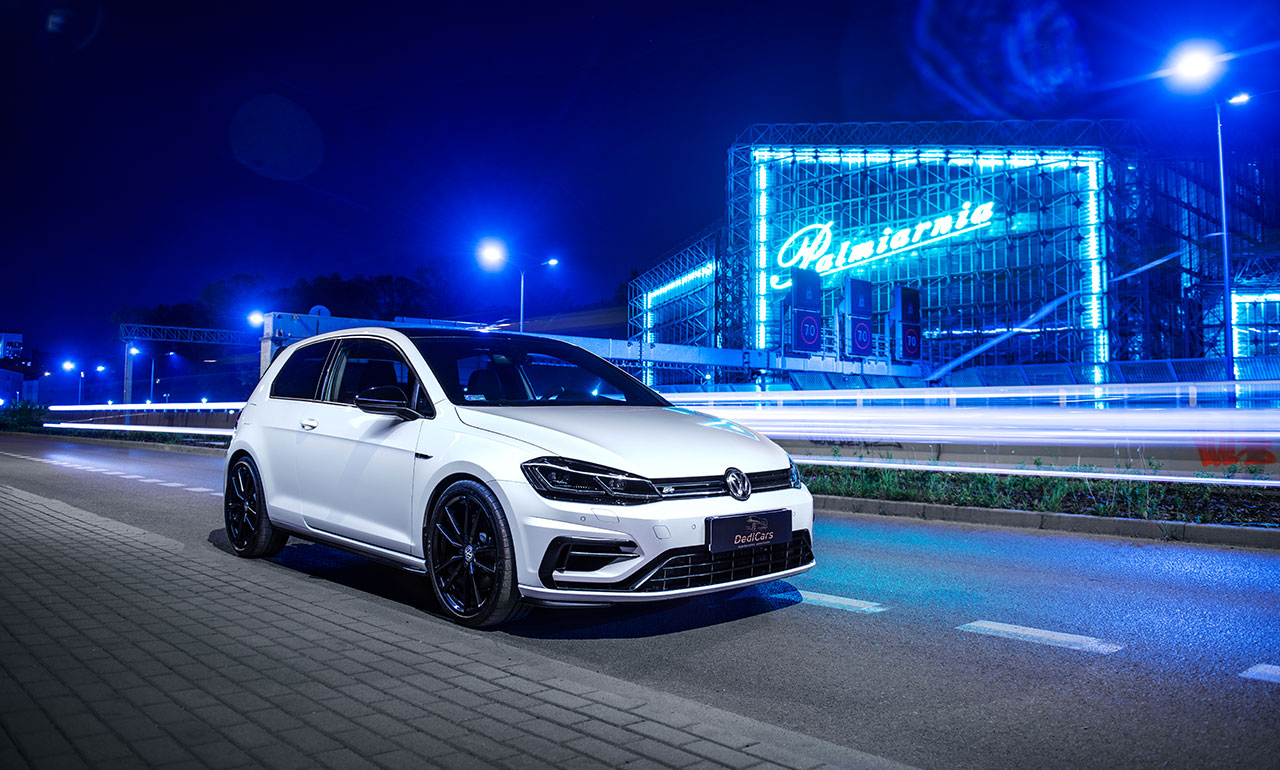 Biały sportowy Volkswagen Golf 7,5R po lifcie na tle neonów