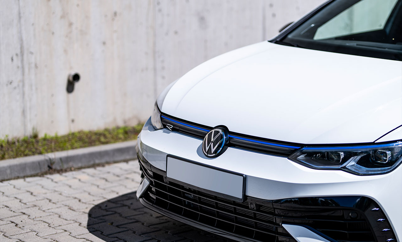 Biały sportowy Volkswagen Golf 8R po lifcie na tle neonów
